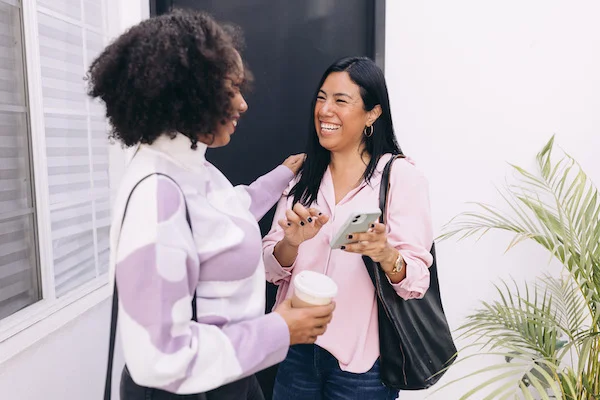Two women talking, one has her hand on the other's shoulder.